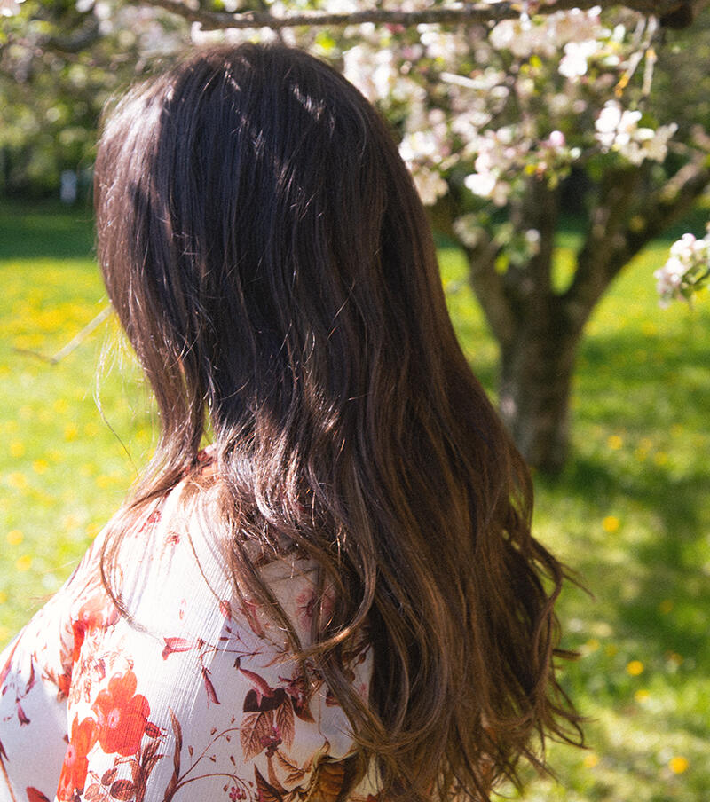 Kvinna framför sommarträdgård med chocolate brown extensions